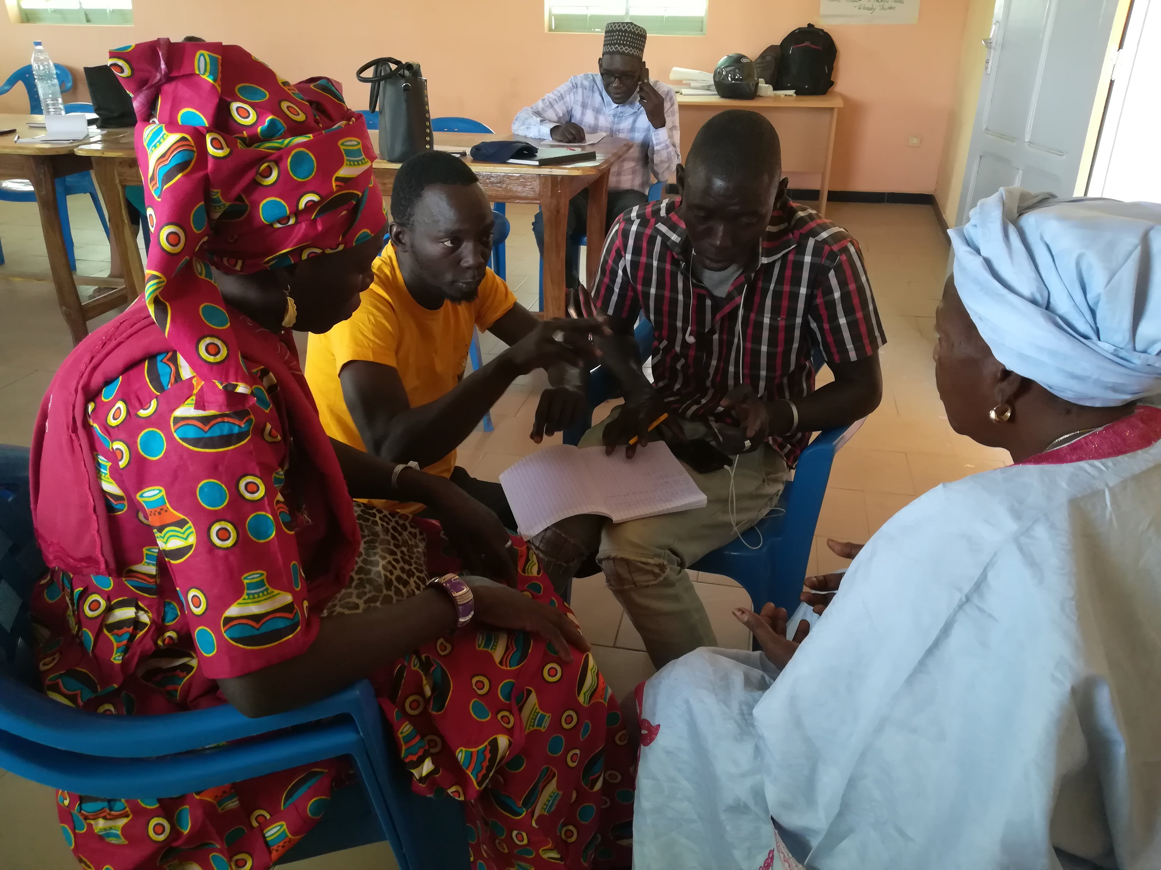 Mor Fall, ELS coördinator in Sokone (gehurkt) legt een evaluatietechniek uit aan de vrouwen van de federatie van Toubacouta. 